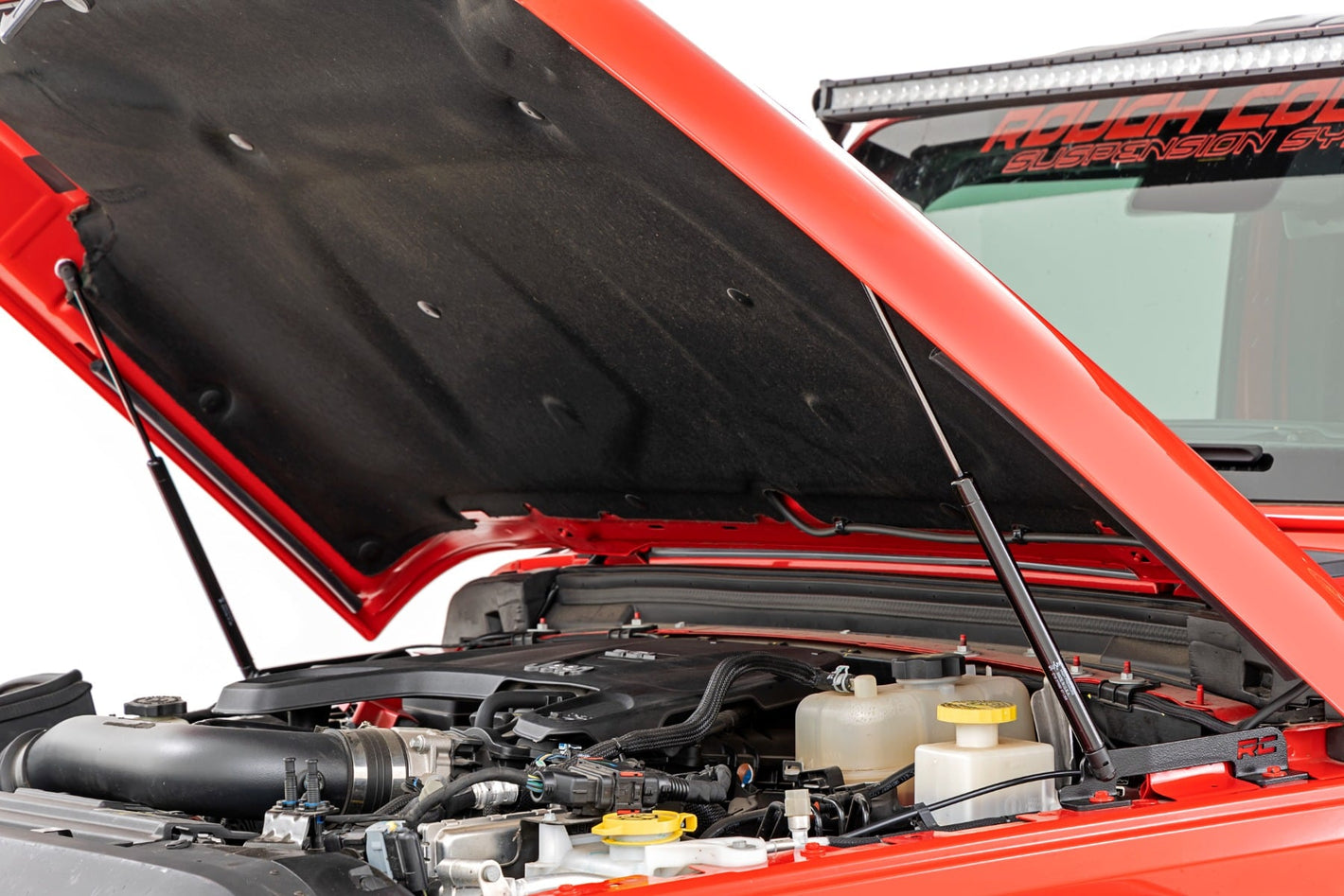 a red jeep sits with an open hood, displaying installed hood struts