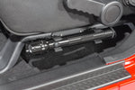 a cropped in photo of a vehicle’s driver seat with a silver metal flashlight mounted beneath