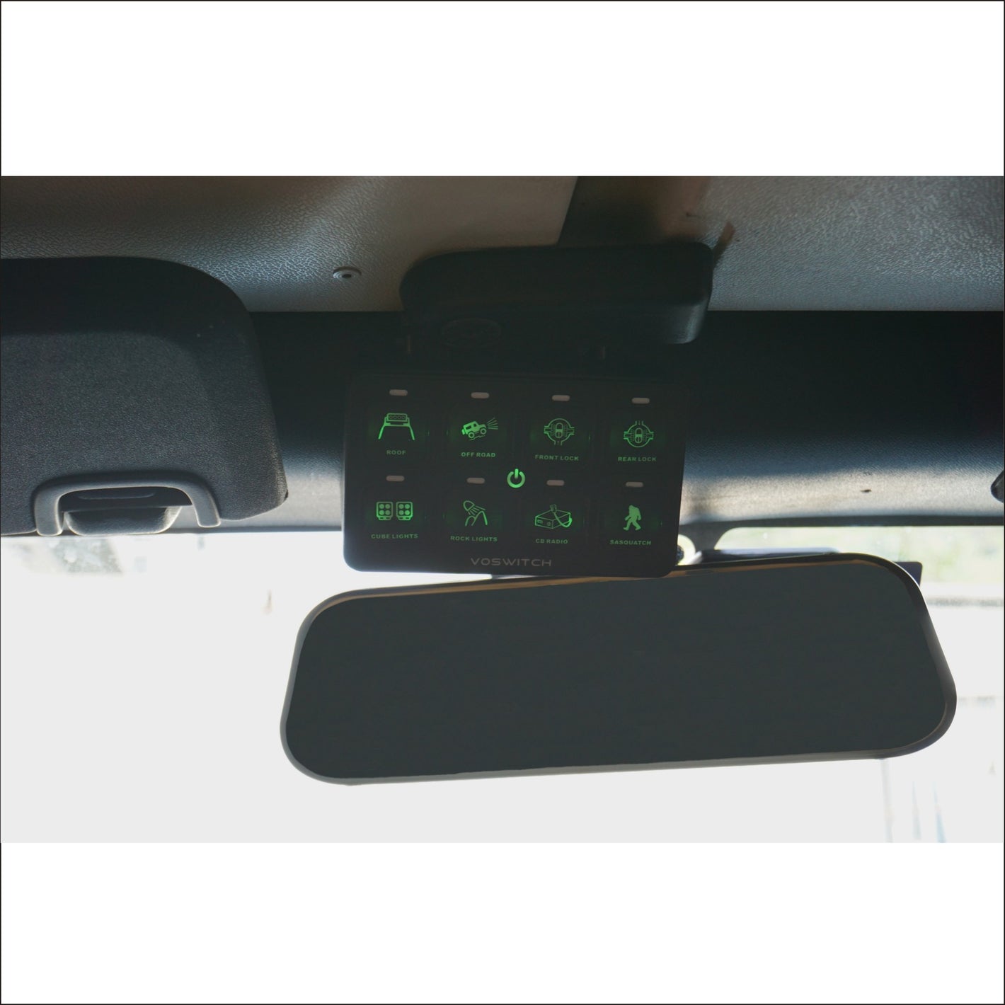 a control system with lit green buttons installed by a rearview mirror