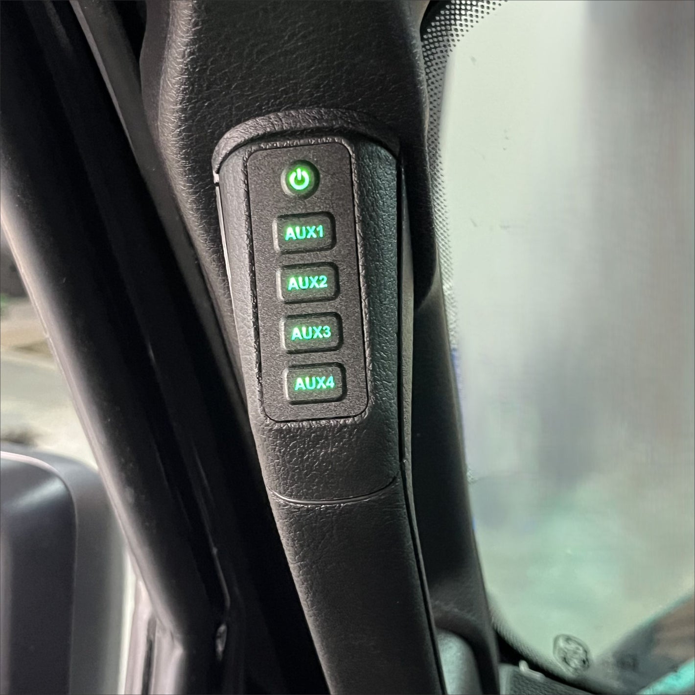 a 4 button panel with green lit buttons installed in a vehicle’s grab handle