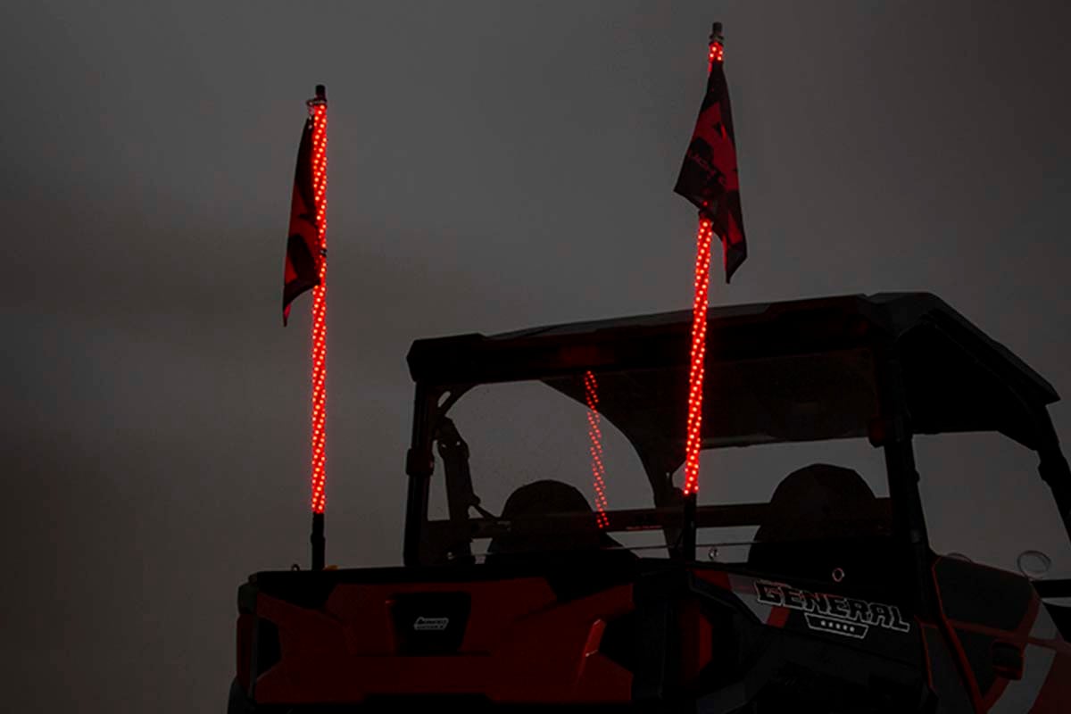 an evening sky with the rear of a jeep showing two illuminated whips