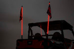 an evening sky with the rear of a jeep showing two illuminated whips
