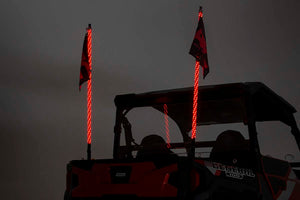 an evening sky with the rear of a jeep showing two illuminated whips