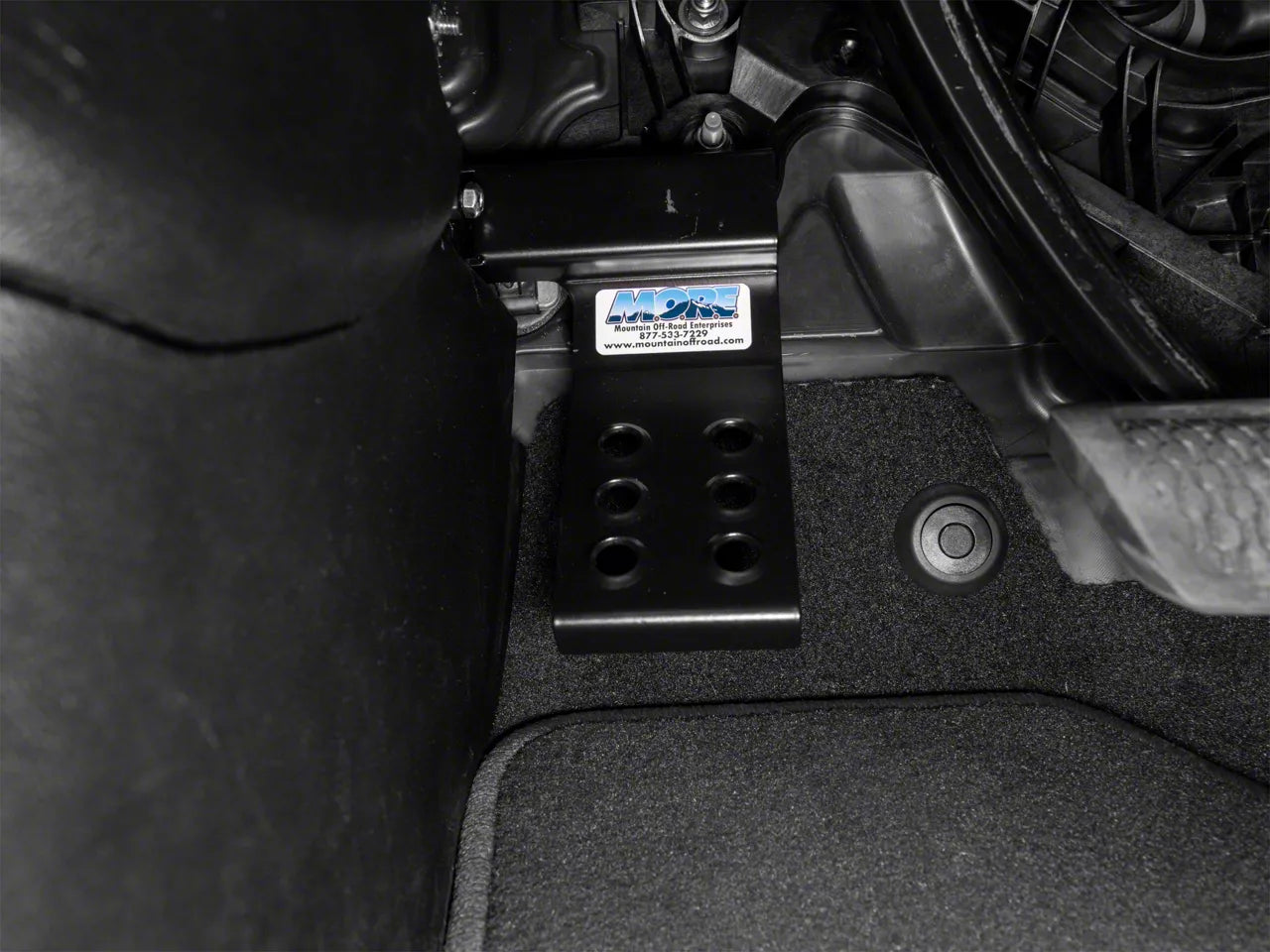 a MORE dead pedal sits installed in the floorboard of a jeep wrangler