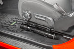 a cropped in photo of a red vehicle’s driver seat with a black metal flashlight mounted beneath