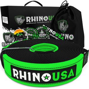 a green and black tow strap is coiled up in front of its packaging and drawstring carrying bag