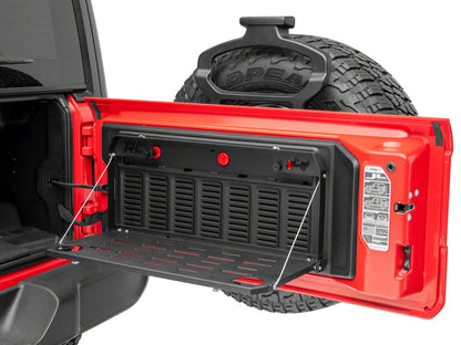 the rear door of a red vehicle is open to reveal an installed tailgate table which has been opened